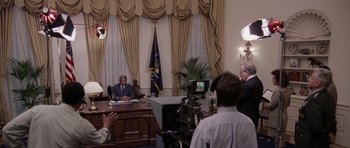 Movie still from “Deep Impact” (1998), directed by Mimi Leder – A man sitting at a desk in front of a camera; Wide shot, Over the shoulder angle