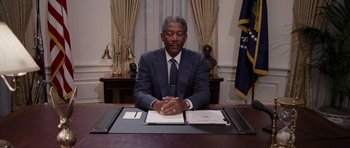 Movie still from “Deep Impact” (1998), directed by Mimi Leder – A man sitting at a desk in front of papers; Medium shot, Low angle