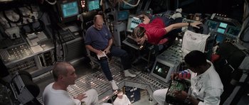 Movie still from “Deep Impact” (1998), directed by Mimi Leder – A group of people sitting in a room; Wide shot, High angle