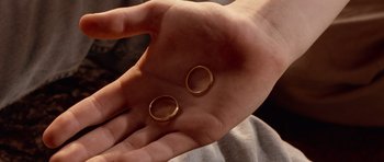 Movie still from “Deep Impact” (1998), directed by Mimi Leder – A hand holding two gold wedding rings in their palm; Extreme Close Up shot, Overhead angle