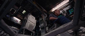 Movie still from “Deep Impact” (1998), directed by Mimi Leder – An older man sitting in a chair in a room; Medium shot, Overhead angle