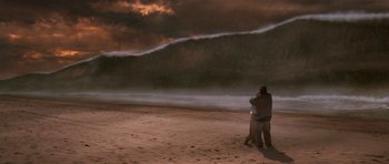 Movie still from “Deep Impact” (1998), directed by Mimi Leder – Two people standing on the beach in front of a wave; Extreme Wide shot, Over the shoulder angle