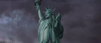 Movie still from “Deep Impact” (1998), directed by Mimi Leder – The statue of liberty is lit up by the light of a candle; Wide shot, Low angle