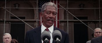 Movie still from “Deep Impact” (1998), directed by Mimi Leder – An older man in a suit and tie speaking into two microphones; Close Up shot, Low angle