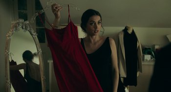 Movie still from “Deep Water” (2022), directed by Adrian Lyne – A woman in a black dress holding a red dress; Medium shot, Over the shoulder angle