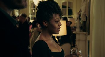 Movie still from “Deep Water” (2022), directed by Adrian Lyne – A woman in a black dress holding a glass of water; Close Up shot, Over the shoulder angle