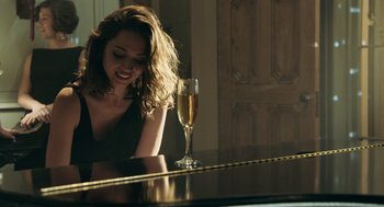 Movie still from “Deep Water” (2022), directed by Adrian Lyne – A woman sitting at a table next to a glass of champagne; Medium shot, Over the shoulder angle
