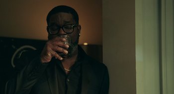 Movie still from “Deep Water” (2022), directed by Adrian Lyne – A man drinking a glass of wine in a dark room; Medium shot, Over the shoulder angle