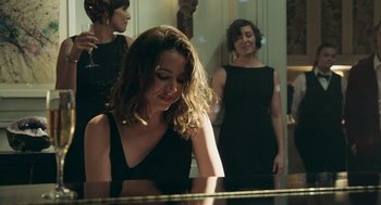 A woman in a black dress is looking at her reflection in a mirror