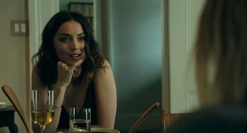 Movie still from “Deep Water” (2022), directed by Adrian Lyne – A woman sitting at a table with a glass of water; Close Up shot, Over the shoulder angle