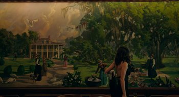 Movie still from “Deep Water” (2022), directed by Adrian Lyne – A woman standing in front of a large painting; Extreme Wide shot, Over the shoulder angle