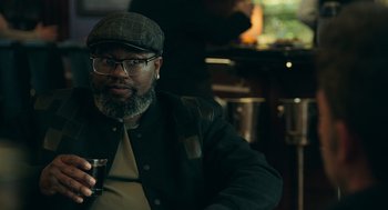 Movie still from “Deep Water” (2022), directed by Adrian Lyne – A man with a beard wearing glasses and a hat; Close Up shot, Over the shoulder angle