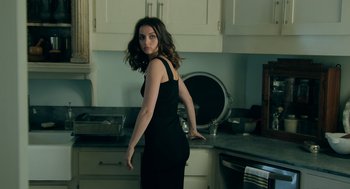 Movie still from “Deep Water” (2022), directed by Adrian Lyne – A woman in a black dress standing in a kitchen next to an oven; Medium shot, Over the shoulder angle