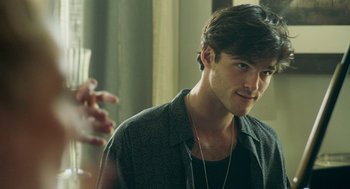 Movie still from “Deep Water” (2022), directed by Adrian Lyne – A man with a beard and a necklace is looking at the camera; Close Up shot, Over the shoulder angle