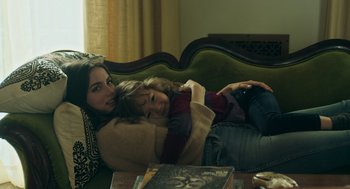 Movie still from “Deep Water” (2022), directed by Adrian Lyne – Two women are sitting on a green couch; Medium shot, High angle