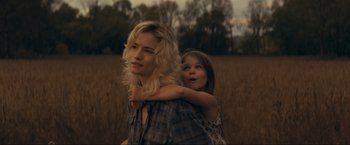 A woman and a girl are standing in a field