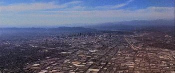 Movie still from “Detective Knight: Independence” (2023), directed by Edward Drake – An aerial view of a large city in the middle of the day; Extreme Wide shot, High angle