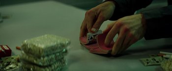 Movie still from “Detective Knight: Redemption” (2022), directed by Edward Drake – A person holding a deck of playing cards on top of a table; Extreme Close Up shot, High angle
