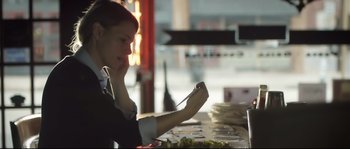 Movie still from “Upstream Color” (2013), directed by Shane Carruth – A woman sitting at a table with a plate of food in front of her face; Medium shot, Over the shoulder angle