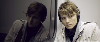 Movie still from “Upstream Color” (2013), directed by Shane Carruth – A woman with headphones looking into a mirror; Close Up shot, Over the shoulder angle