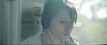 Movie still from “Upstream Color” (2013), directed by Shane Carruth – A woman wearing headphones looking at the camera; Close Up shot, Low angle