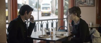 Movie still from “Upstream Color” (2013), directed by Shane Carruth – A man and a woman sitting at a table with plates of food; Medium shot, Over the shoulder angle