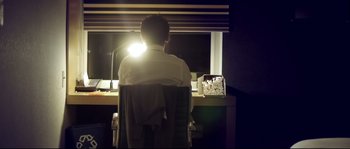 Movie still from “Upstream Color” (2013), directed by Shane Carruth – A man sitting in front of a window at night; Medium shot, Low angle