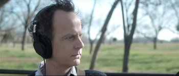 Movie still from “Upstream Color” (2013), directed by Shane Carruth – A person wearing headphones near a tree; Close Up shot, Over the shoulder angle