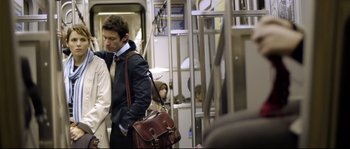 Movie still from “Upstream Color” (2013), directed by Shane Carruth – A man in a suit and tie holding a brown bag; Medium shot, Over the shoulder angle