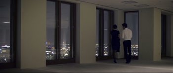Movie still from “Upstream Color” (2013), directed by Shane Carruth – Two women are standing in front of a large window; Wide shot, Low angle