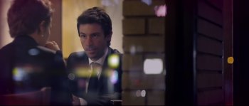 Movie still from “Upstream Color” (2013), directed by Shane Carruth – A man wearing a suit and tie sitting in front of a brick wall; Close Up shot, Over the shoulder angle