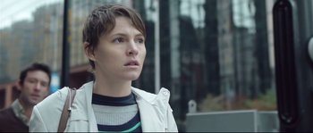 Movie still from “Upstream Color” (2013), directed by Shane Carruth – A woman standing in front of a building looking to her left; Close Up shot, Low angle