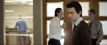 Movie still from “Upstream Color” (2013), directed by Shane Carruth – A man in a suit and tie standing next to another man in a suit and tie; Medium shot, Over the shoulder angle