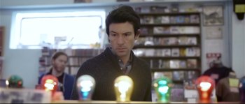 Movie still from “Upstream Color” (2013), directed by Shane Carruth – A man is looking at some light bulbs in a store; Close Up shot, Over the shoulder angle