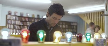 Movie still from “Upstream Color” (2013), directed by Shane Carruth – A man sitting in front of a row of light bulbs; Close Up shot, Low angle