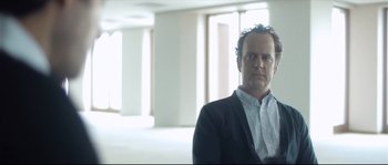 Movie still from “Upstream Color” (2013), directed by Shane Carruth – A man standing in an empty room wearing a suit; Medium shot, Low angle