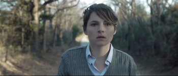 Movie still from “Upstream Color” (2013), directed by Shane Carruth – A woman in a white shirt and a gray sweater; Close Up shot, Over the shoulder angle