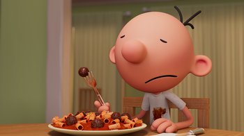 Movie still from “Diary of a Wimpy Kid” (2021), directed by Gino Nichele – A charlie brown character sitting in front of a plate of food; Medium shot, High angle