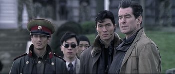 Movie still from “Die Another Day” (2002), directed by Lee Tamahori – A group of men standing next to each other on a street; Close Up shot, Over the shoulder angle
