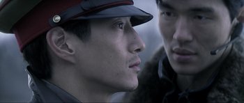 Movie still from “Die Another Day” (2002), directed by Lee Tamahori – A man wearing a red hat and a man wearing a fur coat; Close Up shot, Over the shoulder angle