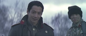 Movie still from “Die Another Day” (2002), directed by Lee Tamahori – A man in a military uniform smiles for the camera; Close Up shot, Over the shoulder angle