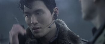 Movie still from “Die Another Day” (2002), directed by Lee Tamahori – A man wearing a fur coat and a headset; Close Up shot, Over the shoulder angle