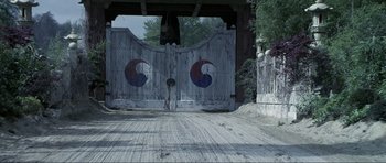 Movie still from “Die Another Day” (2002), directed by Lee Tamahori – An old wooden gate with a red and blue design on it's sides; Wide shot, High angle
