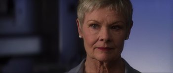 Movie still from “Die Another Day” (2002), directed by Lee Tamahori – An older woman with short blonde hair wearing a blue shirt; Close Up shot, Low angle