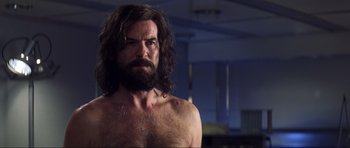 Movie still from “Die Another Day” (2002), directed by Lee Tamahori – A man with long hair and a bare chest; Close Up shot, Over the shoulder angle