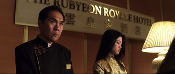 Movie still from “Die Another Day” (2002), directed by Lee Tamahori – A man and a woman standing next to each other in front of a sign; Medium shot, Low angle