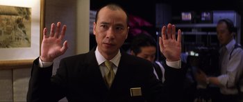 Movie still from “Die Another Day” (2002), directed by Lee Tamahori – A man in a suit and tie holding his hand up in the air; Close Up shot, Low angle