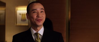 Movie still from “Die Another Day” (2002), directed by Lee Tamahori – A man wearing a suit and tie smiling for the camera; Close Up shot, Low angle