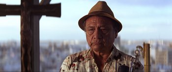 Movie still from “Die Another Day” (2002), directed by Lee Tamahori – An older man wearing a brown hat and a floral shirt; Close Up shot, Low angle