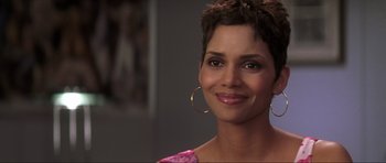 Movie still from “Die Another Day” (2002), directed by Lee Tamahori – A person wearing a dress and smiling; Close Up shot, Over the shoulder angle